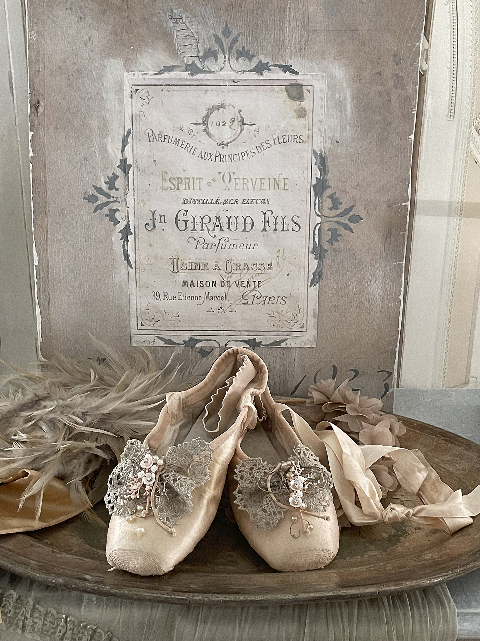 Elegante Ballettschuhe mit zarten Verzierungen auf einem silbernen Tablett Ballettschuhe dekoriert mit Spitze und Perlen auf einem Tablett neben einer Duftflasche