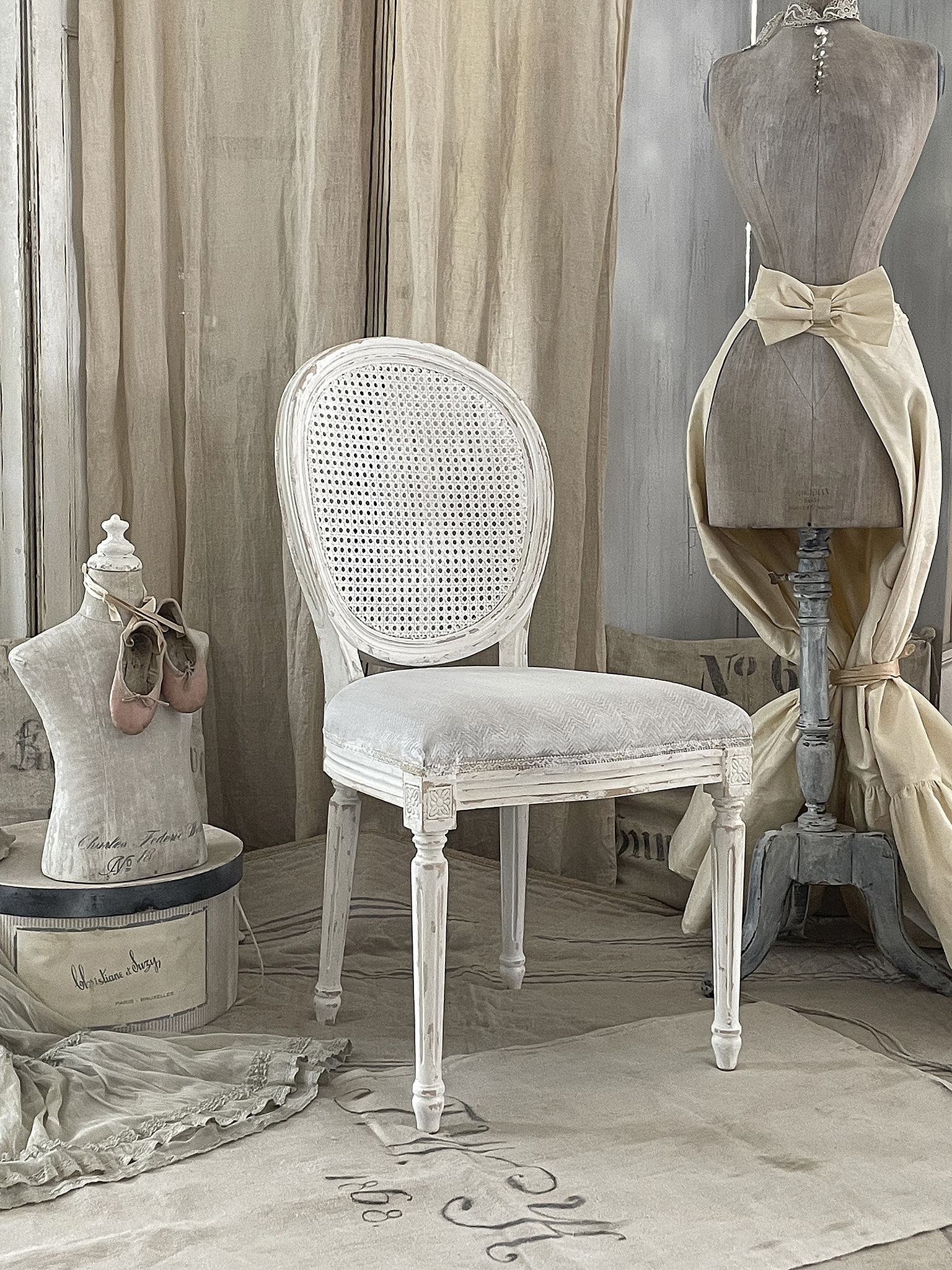 Eleganter weißer Stuhl im Vintage-Stil Weißer Stuhl mit geflochtenem Sitz und romantischer Dekoration im Hintergrund