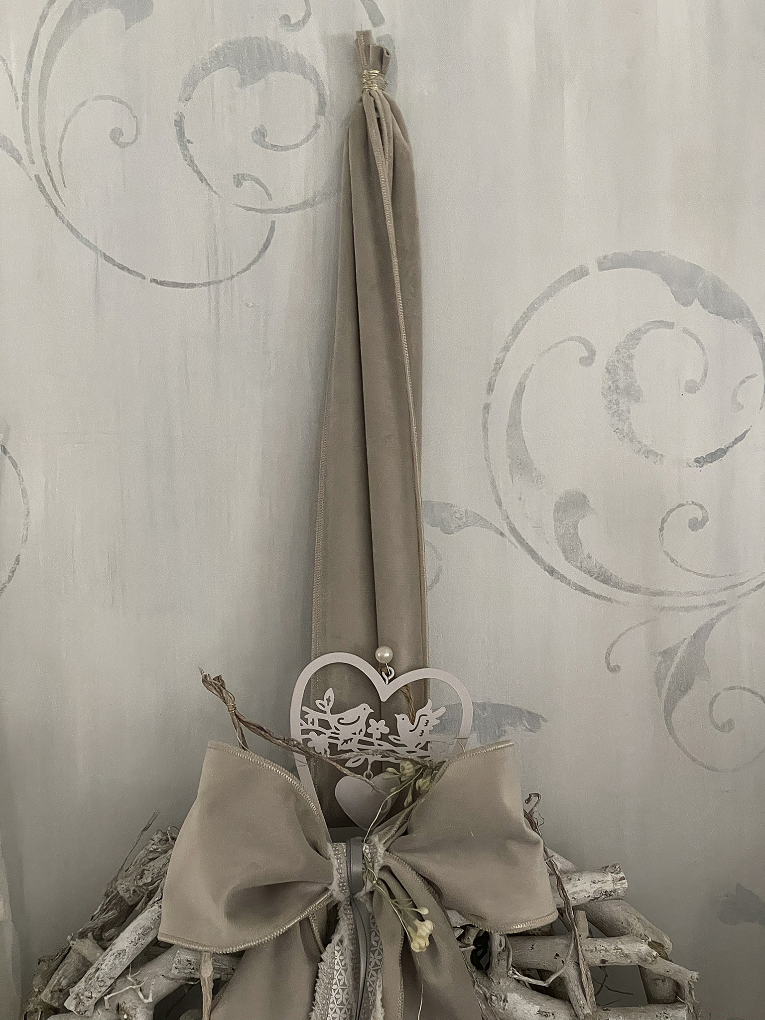 Elegante Dekoration mit einer großen Schleife und einem herzförmigen Anhänger aus Holz.