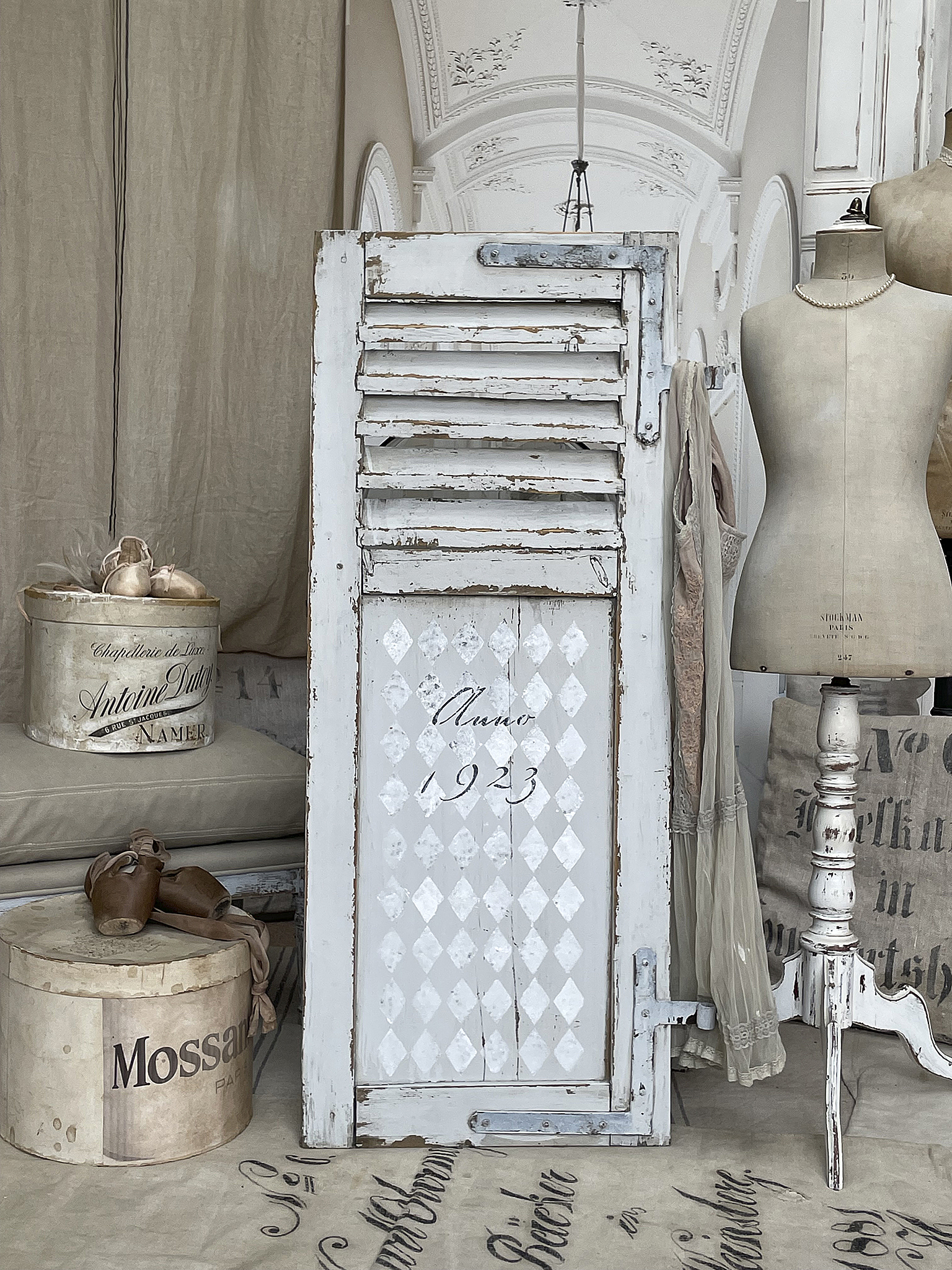 Vintage Shabby Chic Tür mit Jahr 1923 in einem stilvollen Wohnambiente Dekorative vintage Tür mit Shutter-Elementen und dem Jahr 1923, umgeben von stilvollen Wohnaccessoires und einem Mannequin.