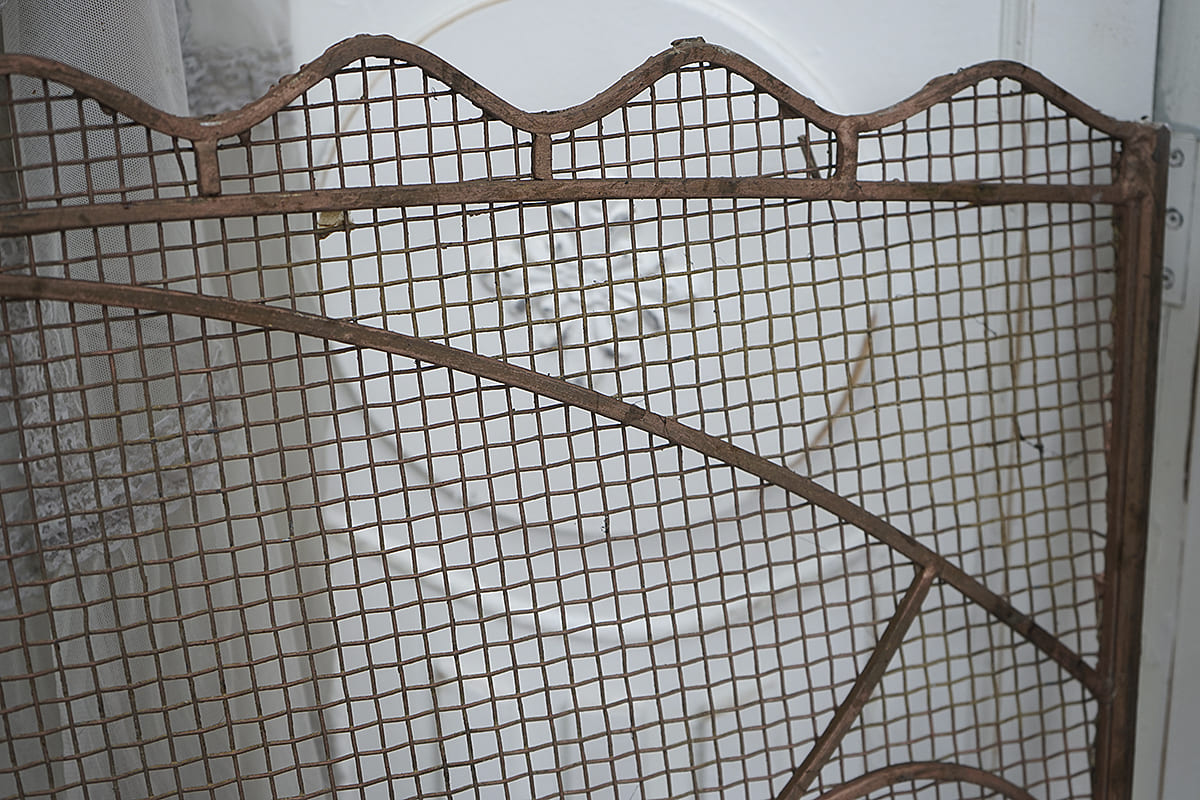 Metallgittertür mit geschwungenem Design, ideal für Vintage-Dekor.