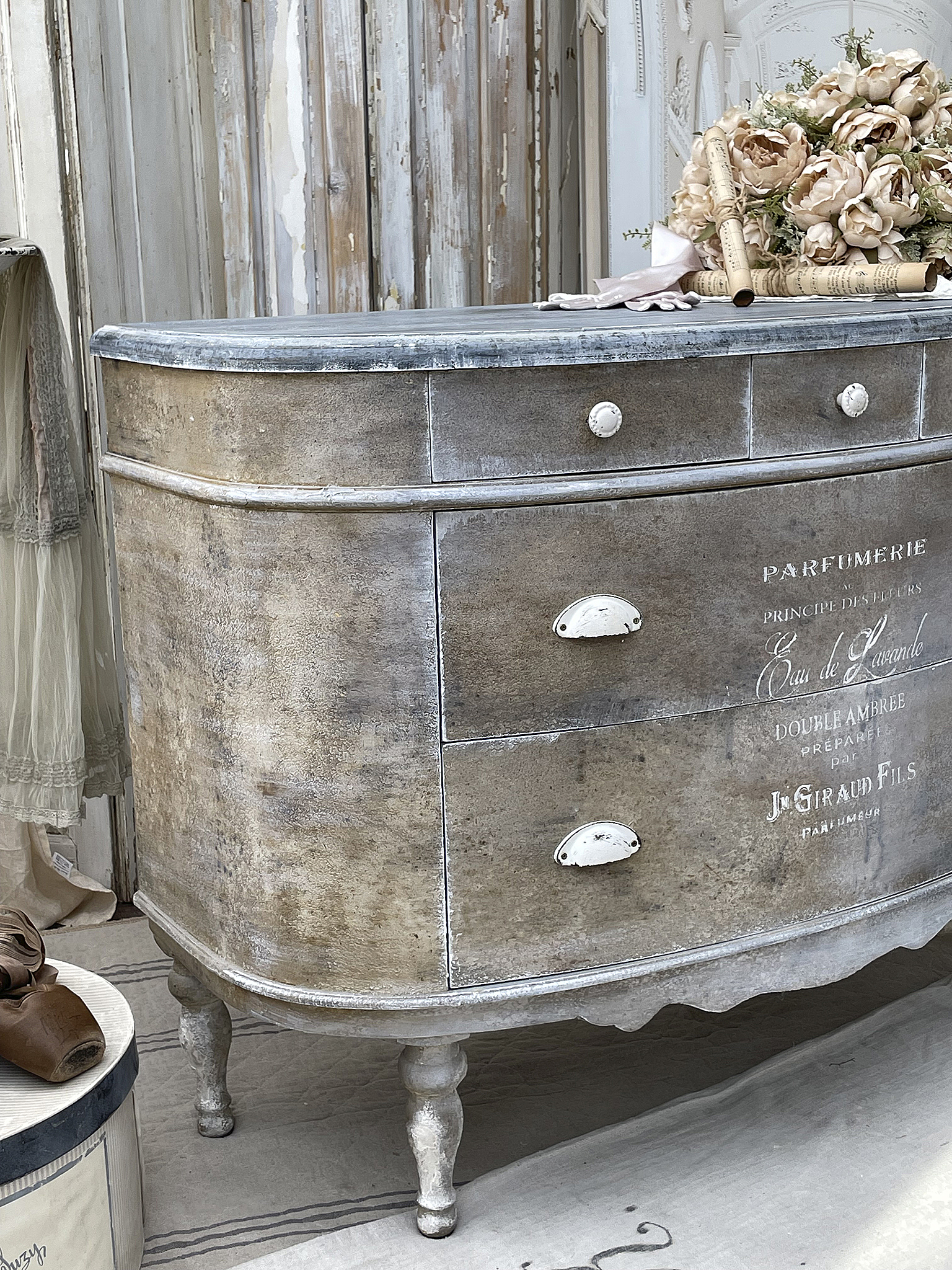 Antiker Kommode im Shabby-Chic-Stil mit Dekoration Antike Shabby-Chic-Kommode mit Blumen und Parfumetikett