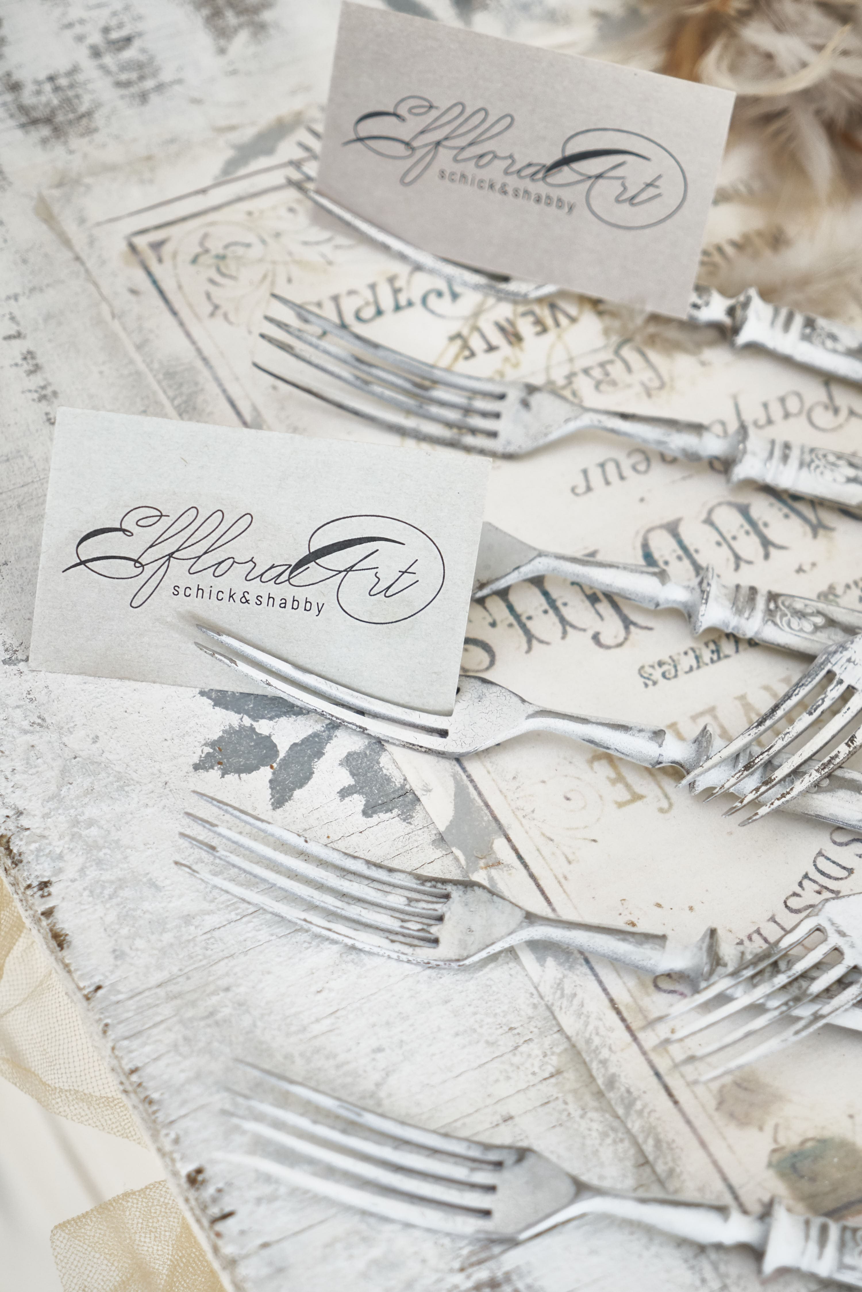 Detailaufnahme von Silbergabeln und Namenskarten auf einem rustikalen Tisch