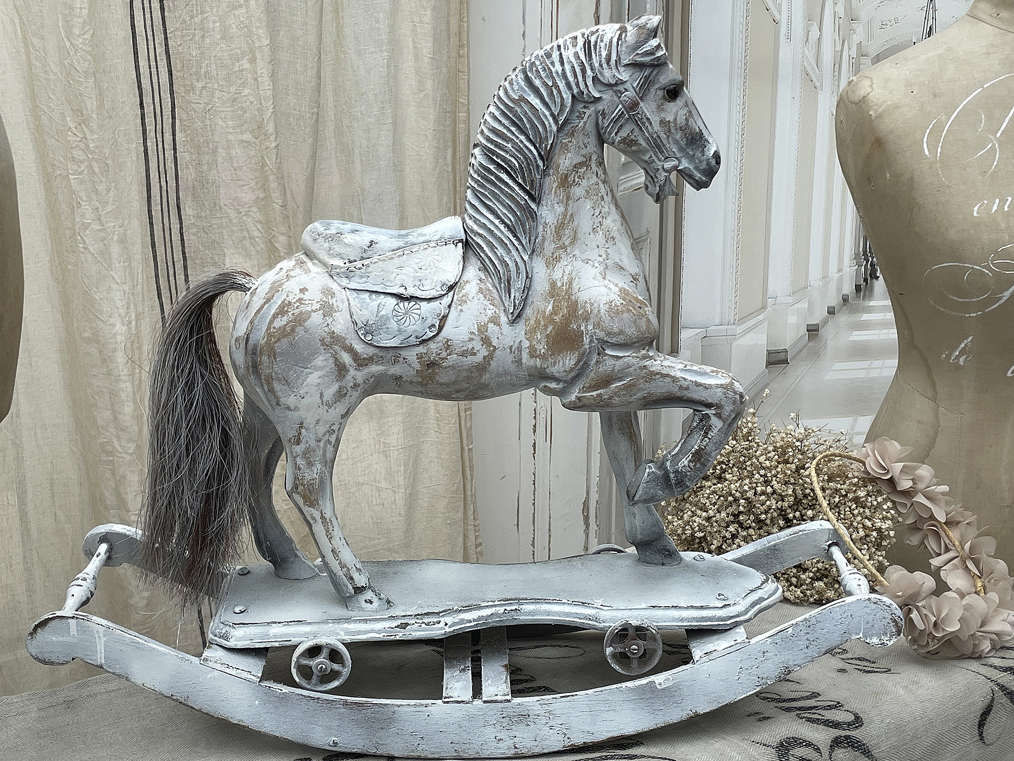 Dekoratives Wippenpferd aus Holz, shabby-chic Style, auf einem Tisch in einem stilvollen Raum