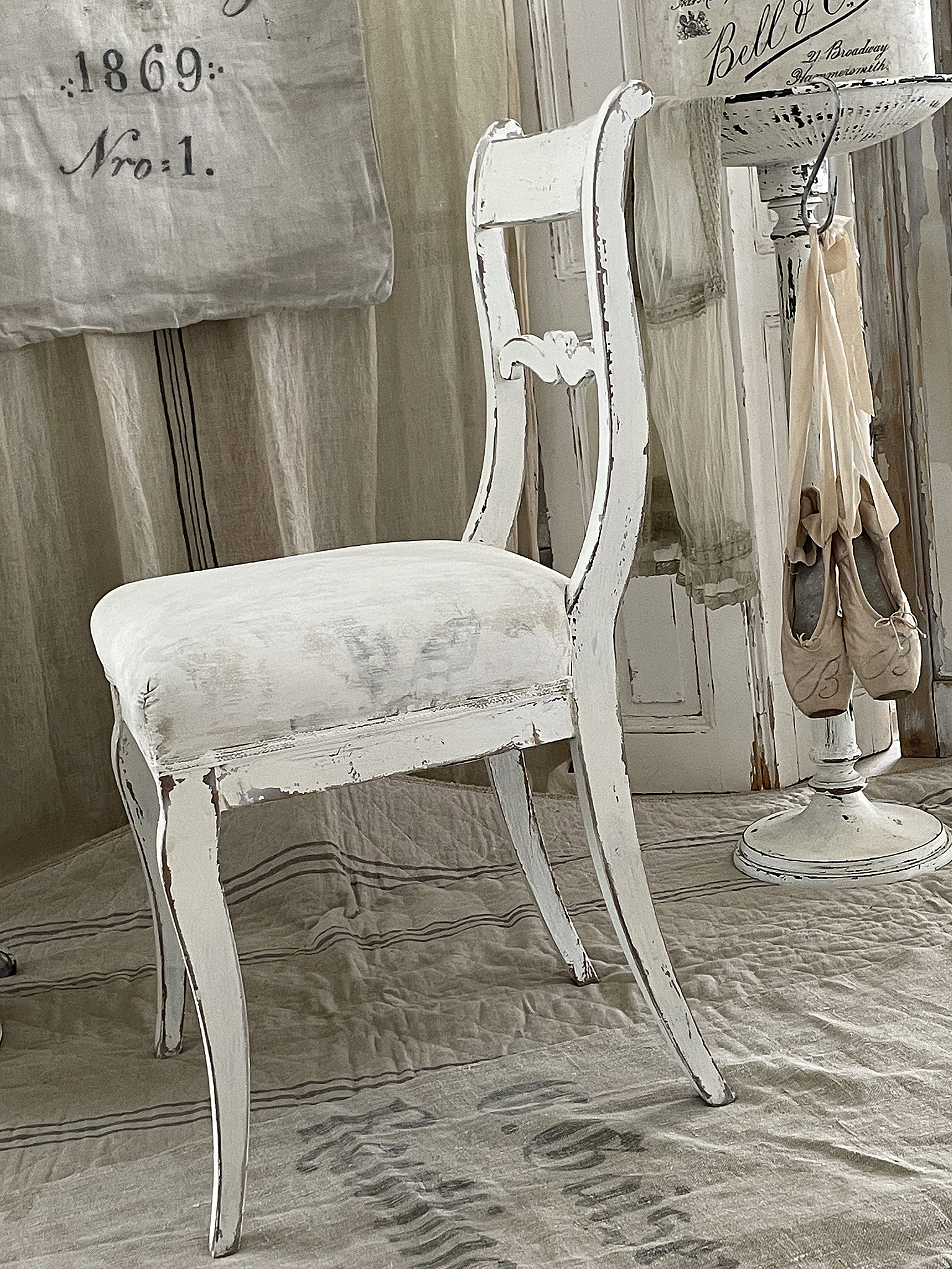 Eleganter weißer Holzstuhl im Vintage-Stil Weißer vintage Holzstuhl mit einem abgenutzten Look in einem hellen Raum