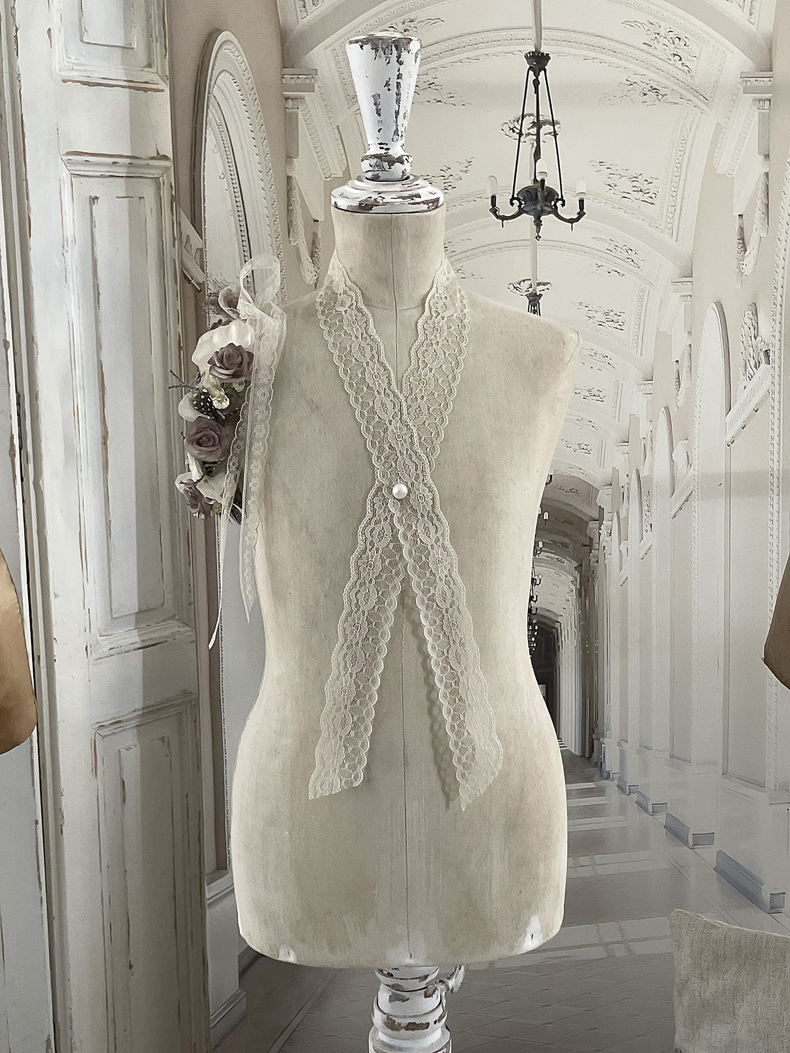 Elegante Mannequin mit Spitze und Blumenarrangement Mannequin mit Spitzenborte und Blumen an der Schulter in stilvollem Ambiente