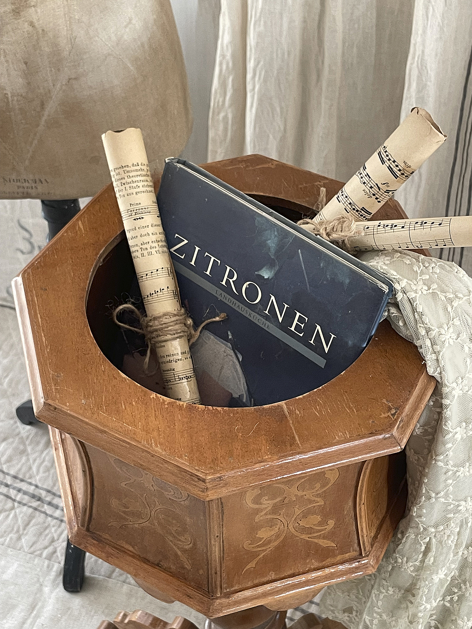 Dekorativer Holzbehälter mit Büchern und Notenrollen Ein stilvoller Holzbehälter mit dem Buch 'Zitronen' und Notenrollen.