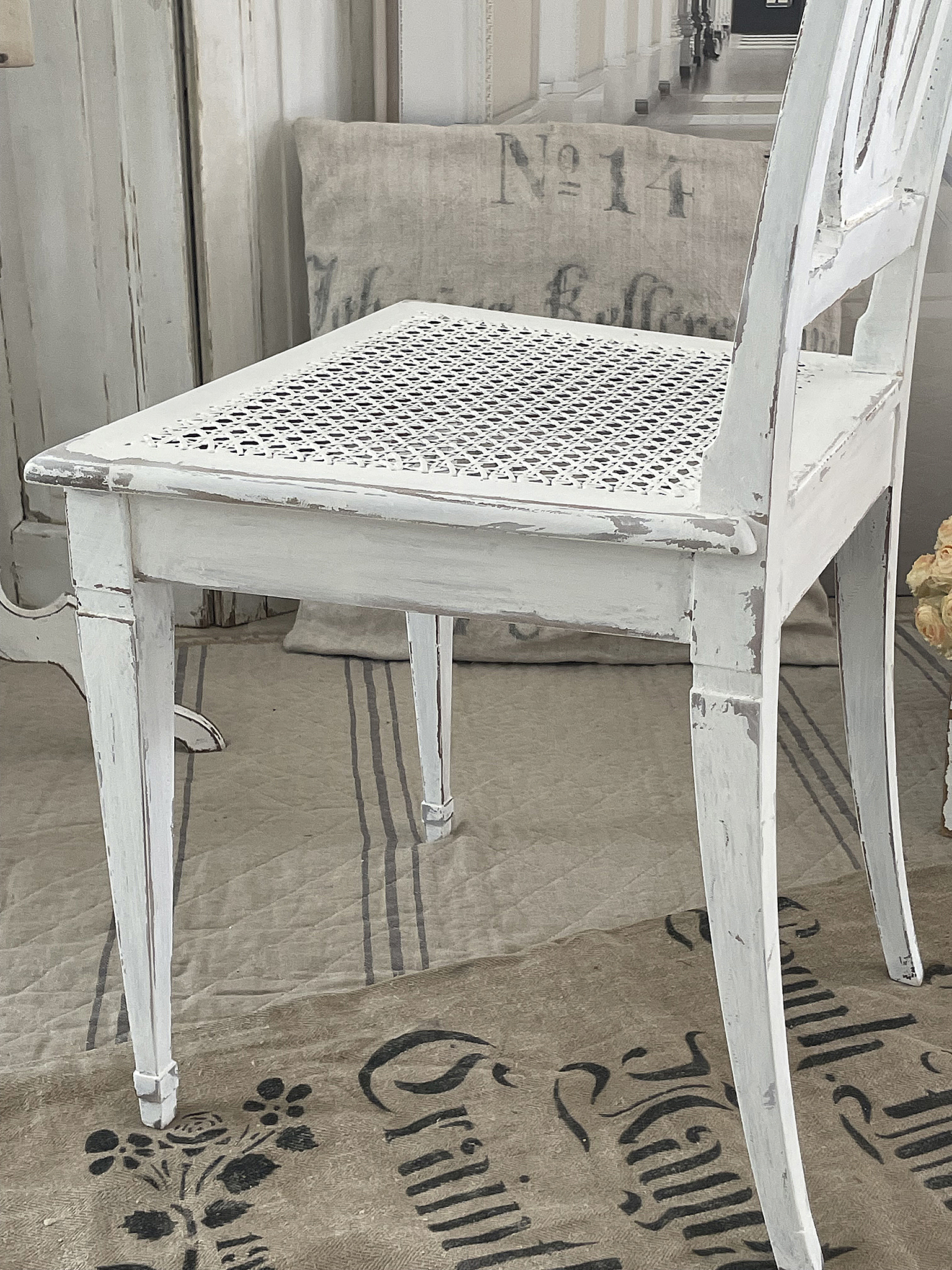 Weißer vintage Stuhl mit geflochtener Sitzfläche Detailansicht eines weißen vintage Stuhls mit geflochtener Sitzfläche und einem dekorativen Untergrund