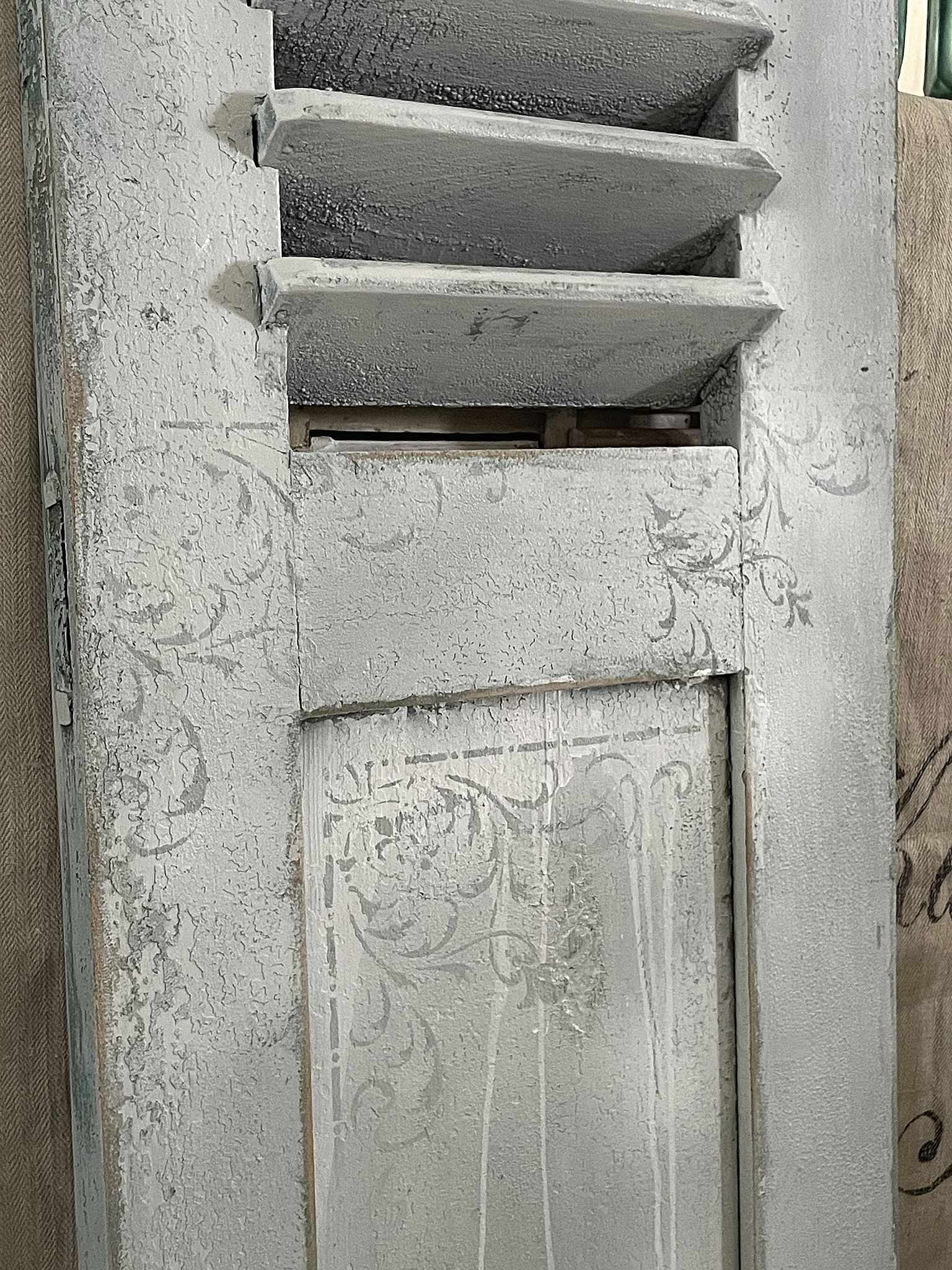 Dekorative graue Fensterläden mit floralen Motiven Detailaufnahme eines grauen Fensterladens mit Schlitzen und verziertem Design