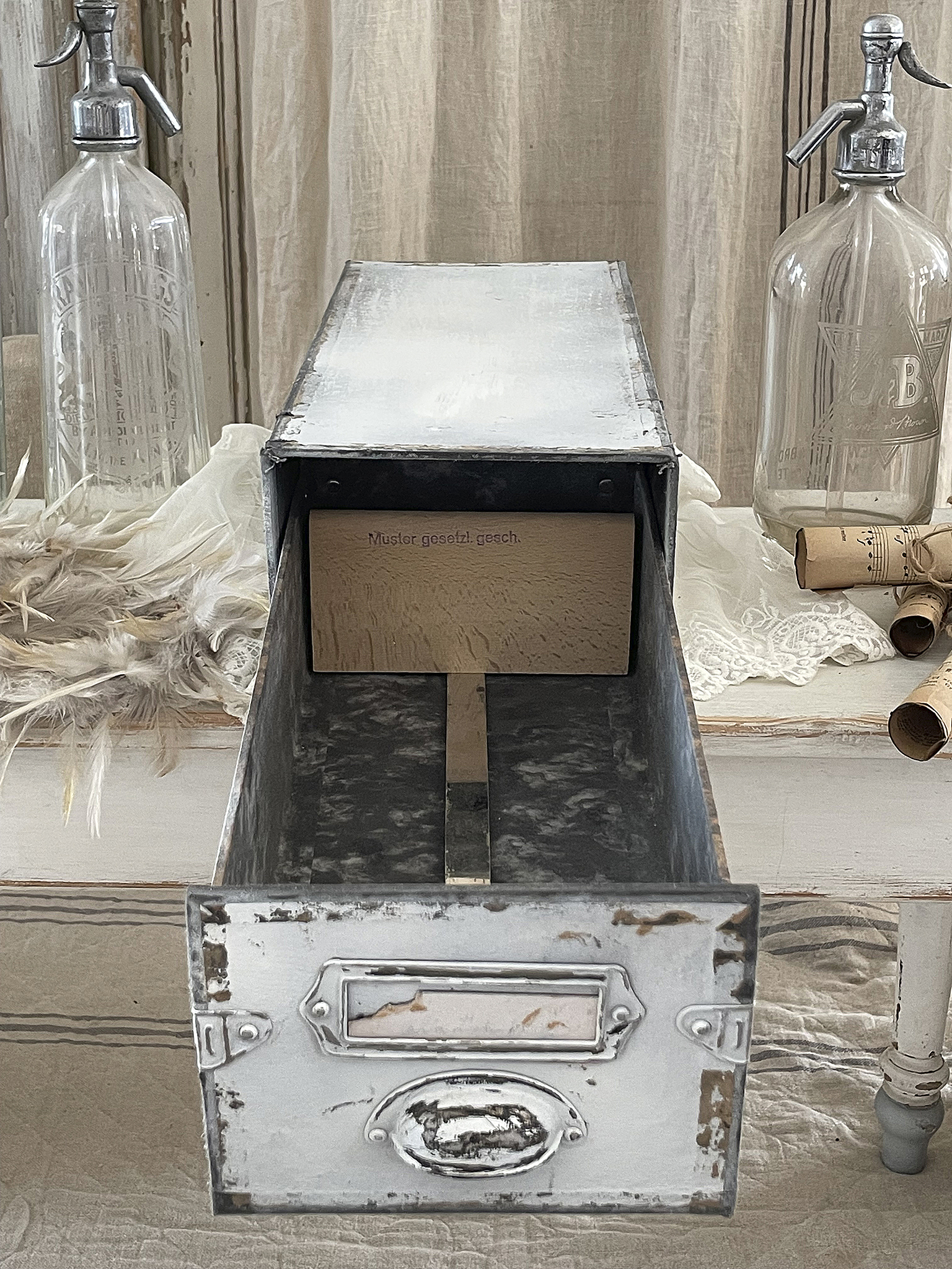 Öffne Vintage Aufbewahrungsbox auf einem Tisch, umgeben von Glaskrügen und Dekoration