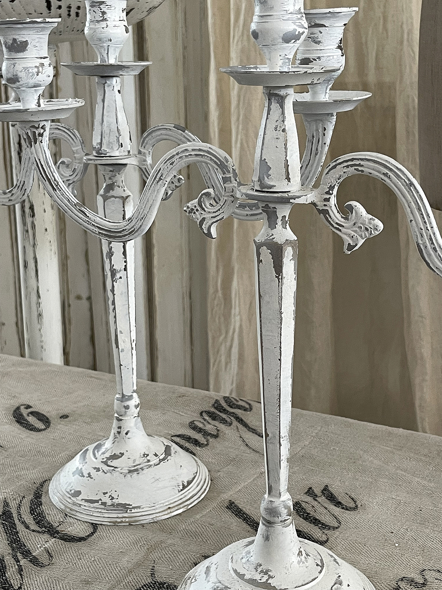 Elegante weiße Kerzenständer im vintage Stil Weiße, antike Kerzenständer mit patiniertem Finish auf einem Tisch
