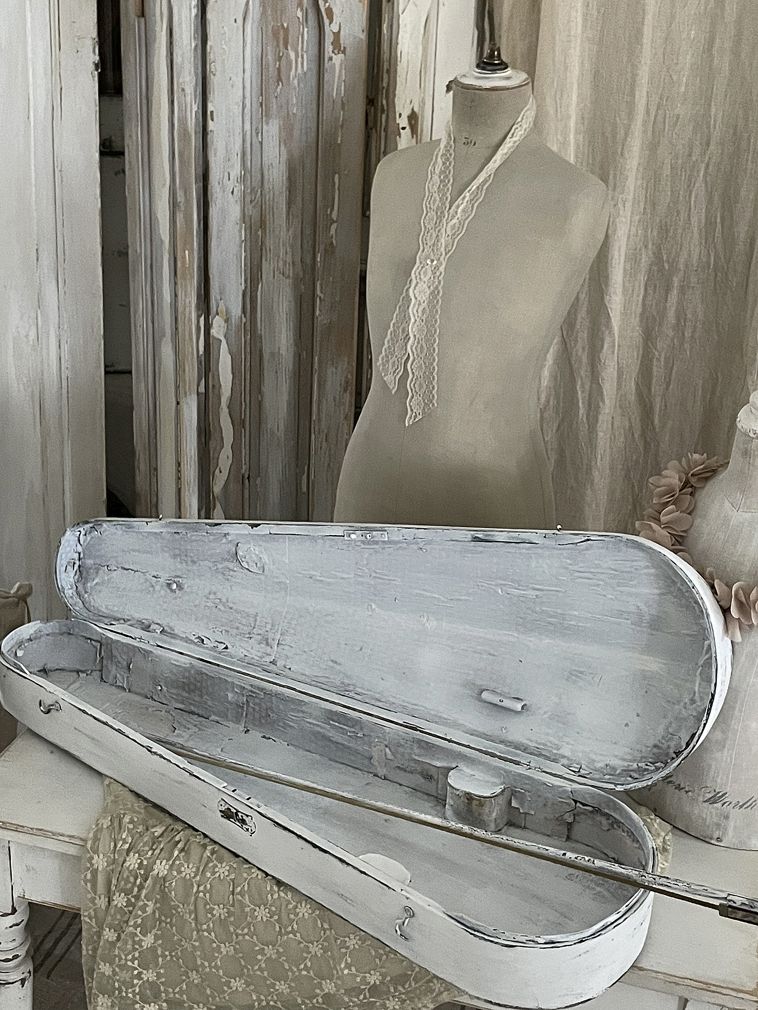 Vintage Aufbewahrungskoffer mit Spitze Offener, nostalgischer Aufbewahrungskoffer aus Holz, dekoriert mit Spitze, auf einem Tisch.