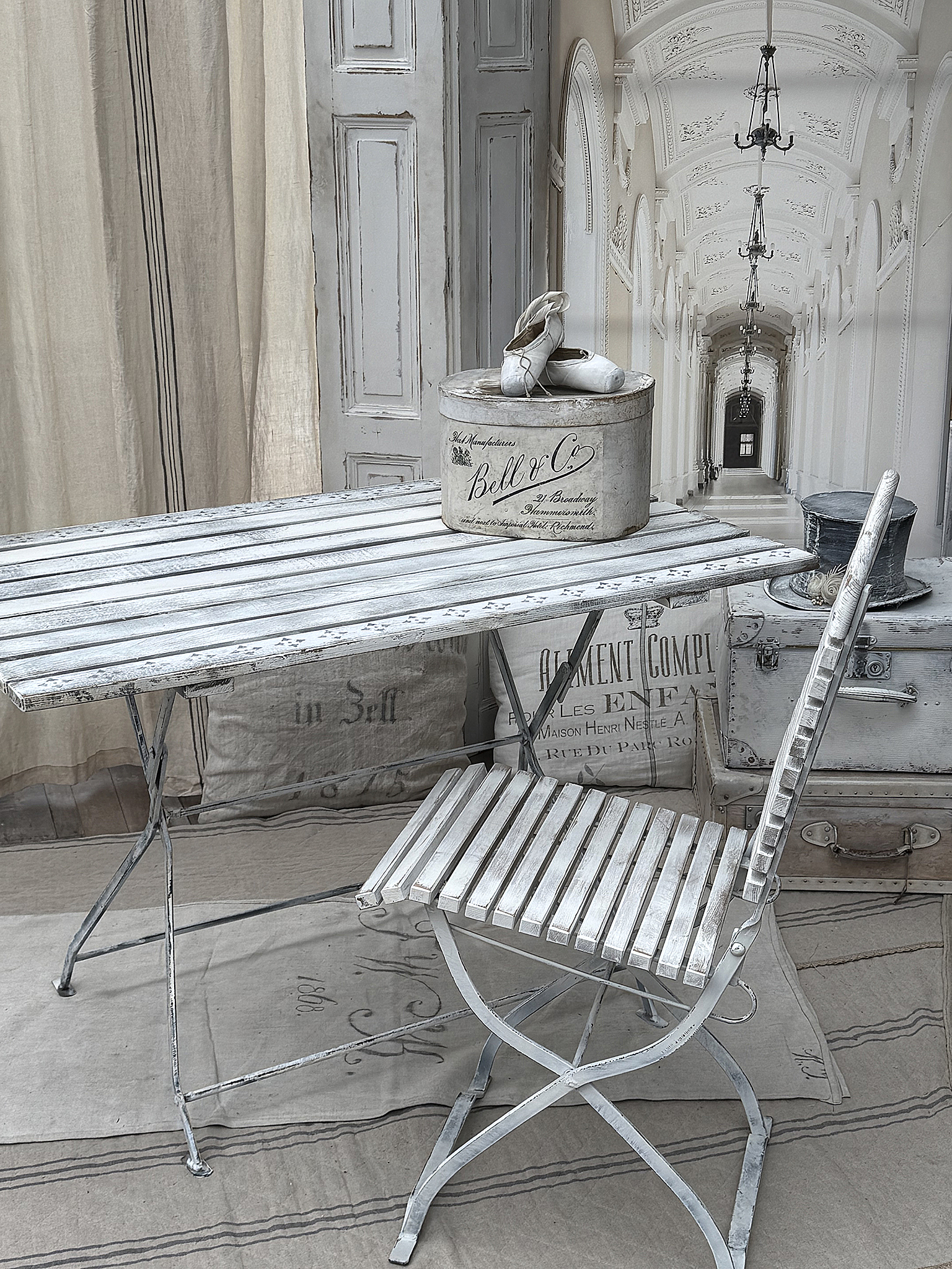 Schöner, eleganter Tisch mit einem weißen Stuhl und nostalgischen Accessoires Ein stilvoller Tisch und Stuhl in Weiß mit nostalgischen Gegenständen auf einem vintage Design-Hintergrund