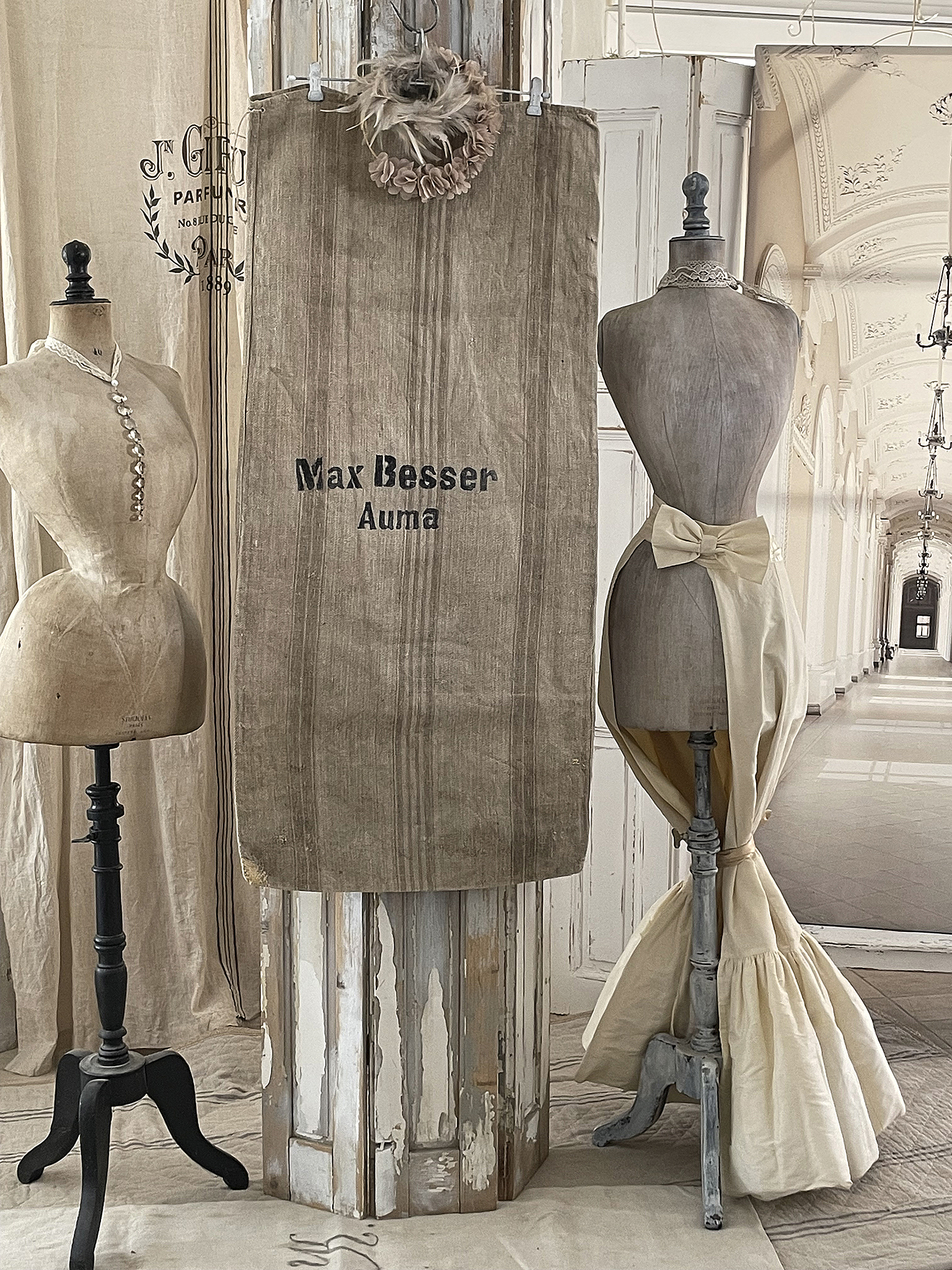 Elegantes Schaufenster mit nostalgischen Schneiderpuppen und einem Leinenbanner Schneiderpuppen, Leinenbanner mit Aufschrift Max Besser, dekorative Elemente in einem stilvollen Ambiente