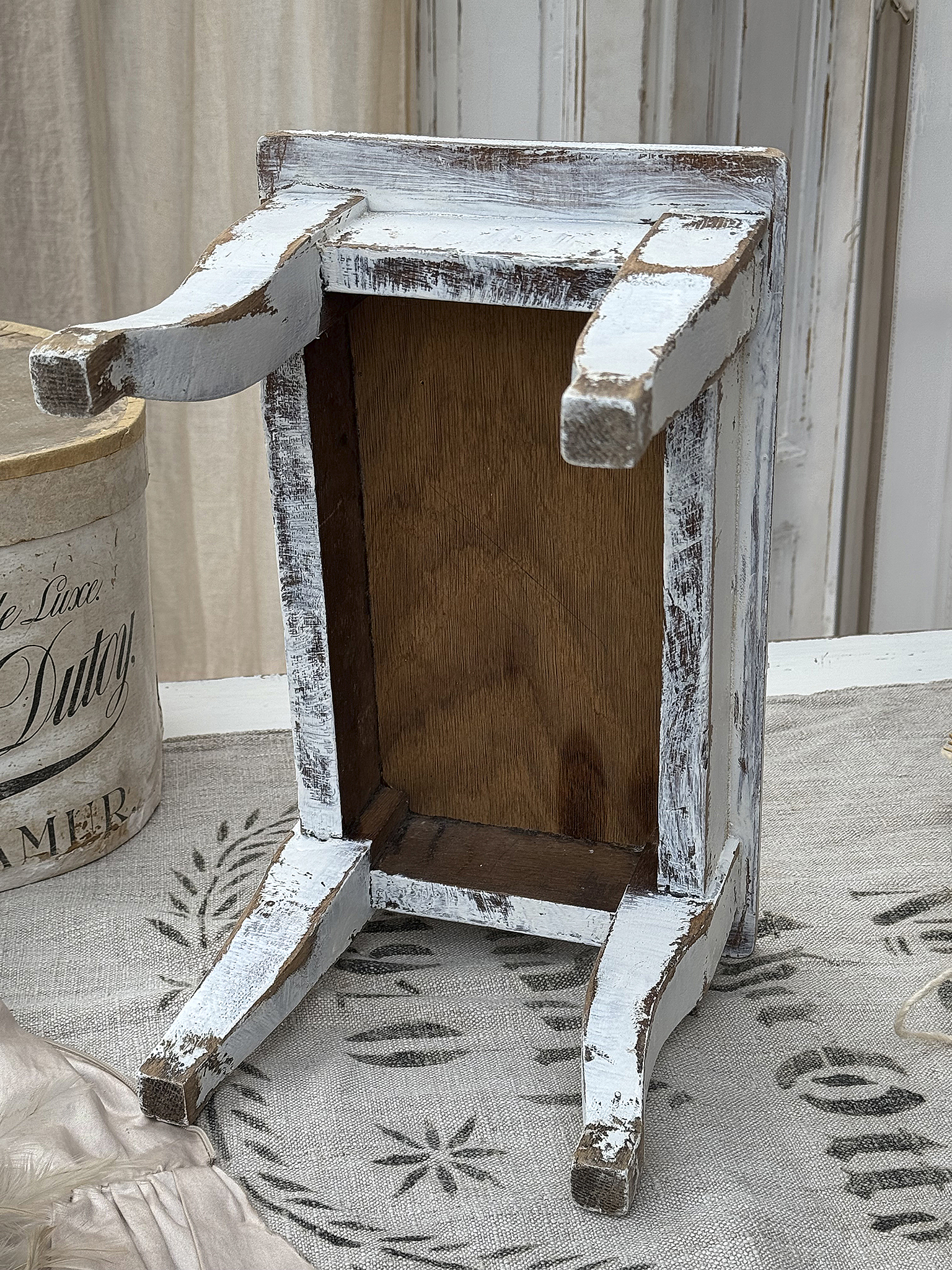 Antiker weißer Holzständer mit rustikalem Charme Antiker Holzständer mit abgenutztem weißen Finish und hölzerner Rückplatte