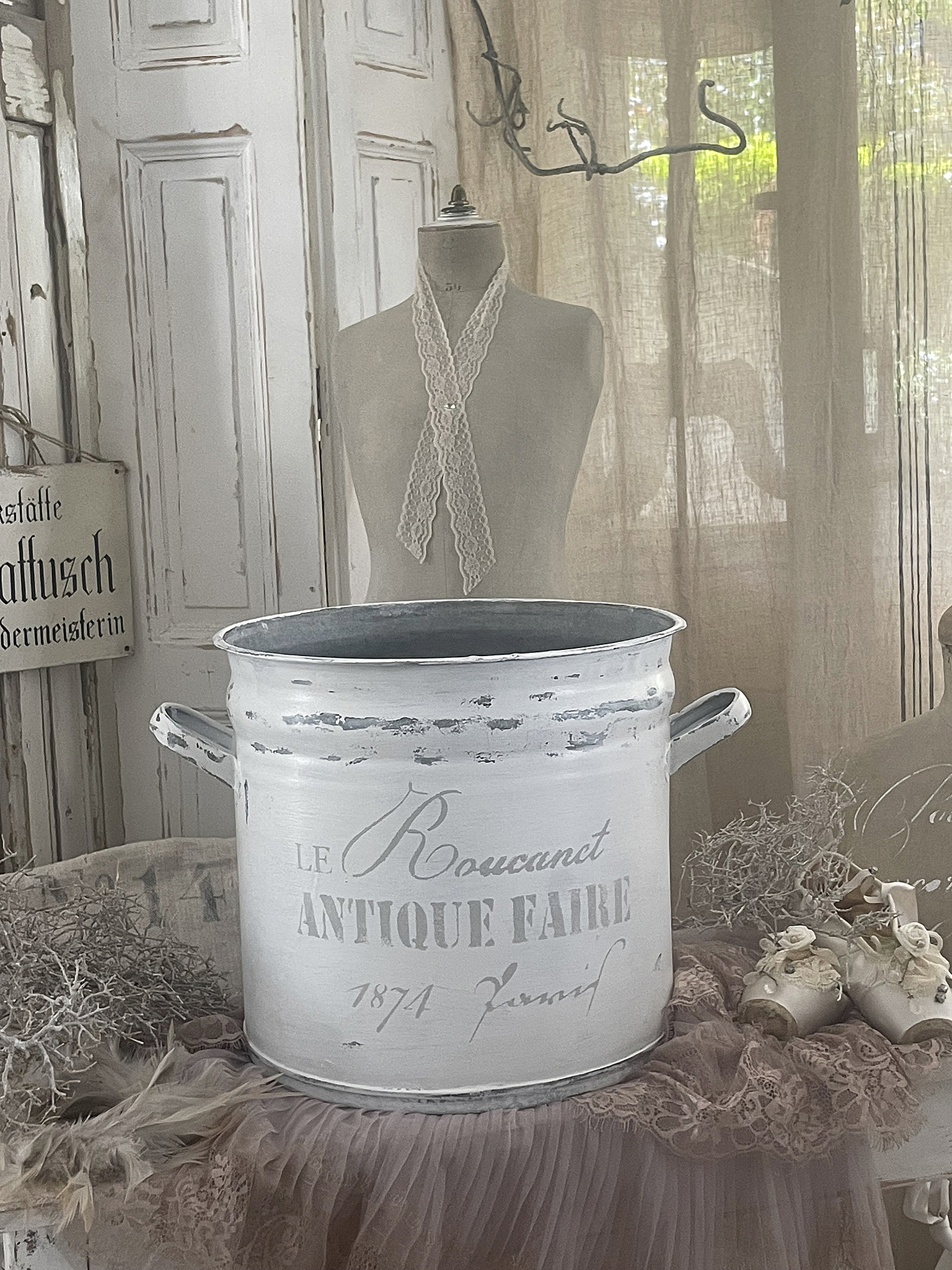 Antike Zinkwanne mit nostalgischem Schriftzug Weiße antike Zinkwanne mit der Aufschrift 'LE Roucant ANTIQUE FAIRE 1874', präsentiert in einem stilvollen Ambiente.
