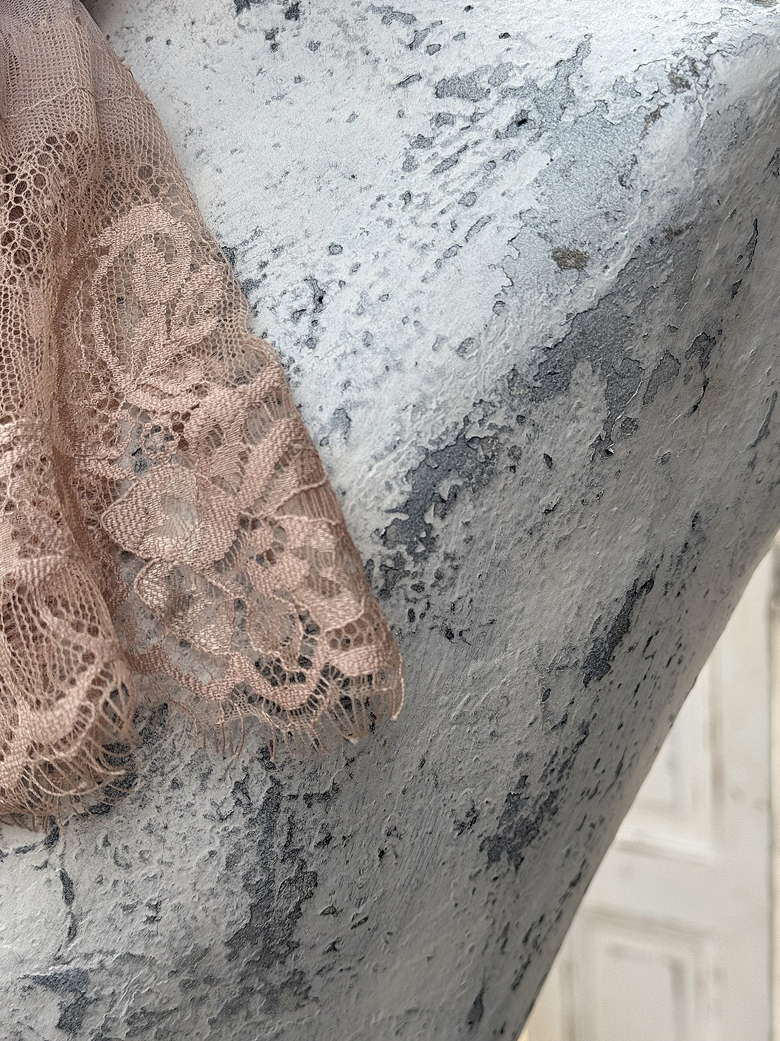 Detailaufnahme von zarter, nude-farbener Spitze auf einer texturierten Oberfläche