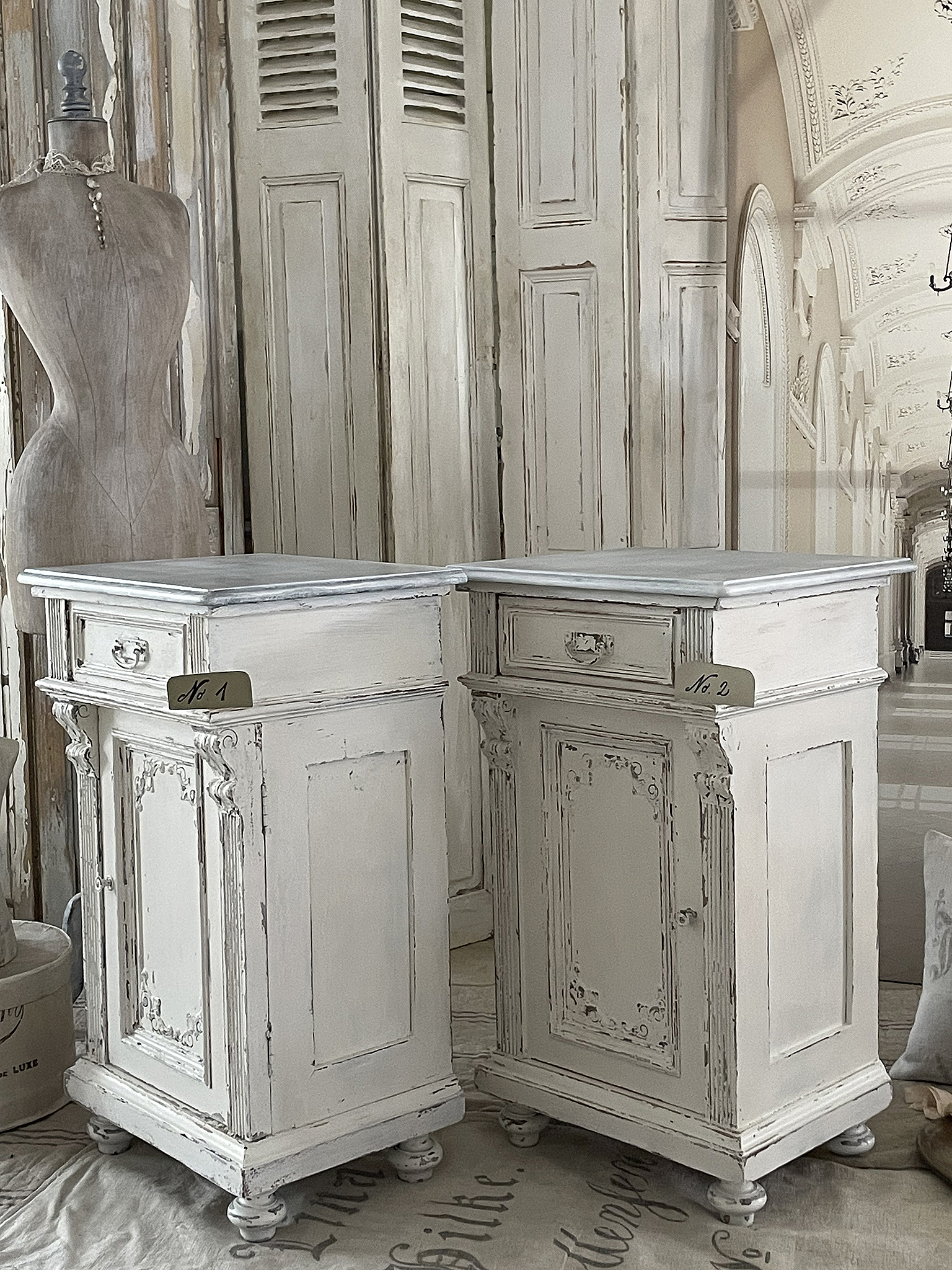 Skandinavische Nachtkommoden im Shabby Chic Stil Zwei elegante Nachtkommoden im Shabby Chic Design, aus einem hellen Holz mit feinen Verzierungen und abgerundeten Füßen.